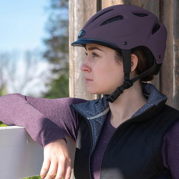 Lady wearing an Aubergine Tipperary Sportage 8500 helmet, looking our a barn window.