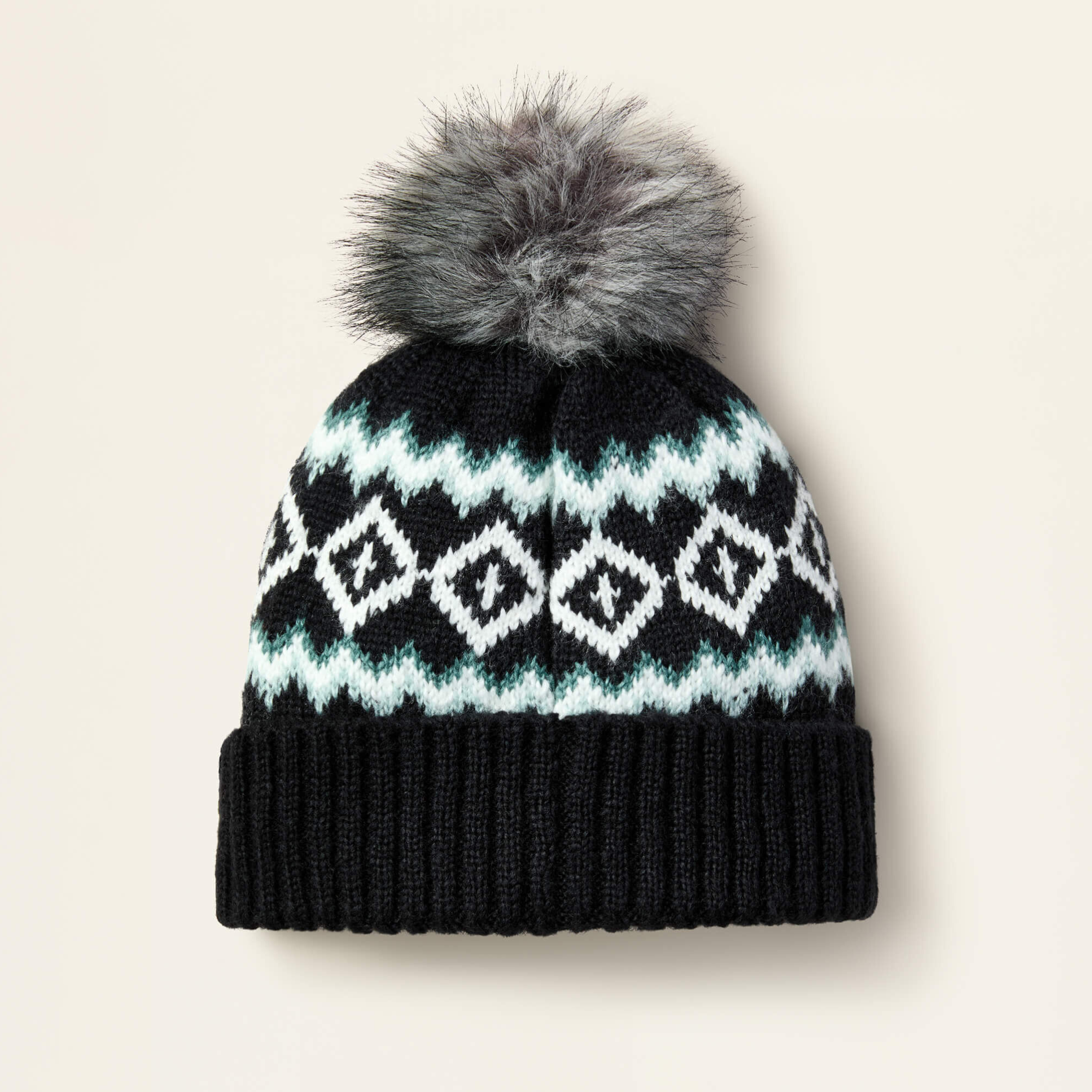 Black Ariat Bristol knit beanie with white and blue pattern and gray fur pom-pom on a light beige background