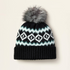 Black Ariat Bristol knit beanie with white and blue pattern and gray fur pom-pom on a light beige background