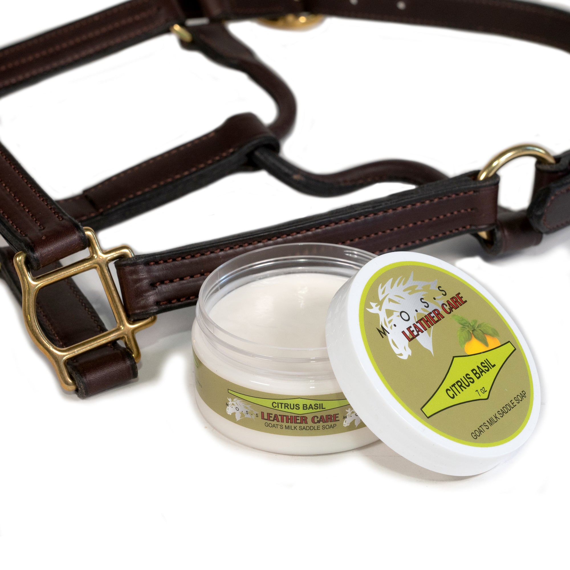 Open container of MOSS Citrus Basil Saddle Soap with a leather bridle on a white background