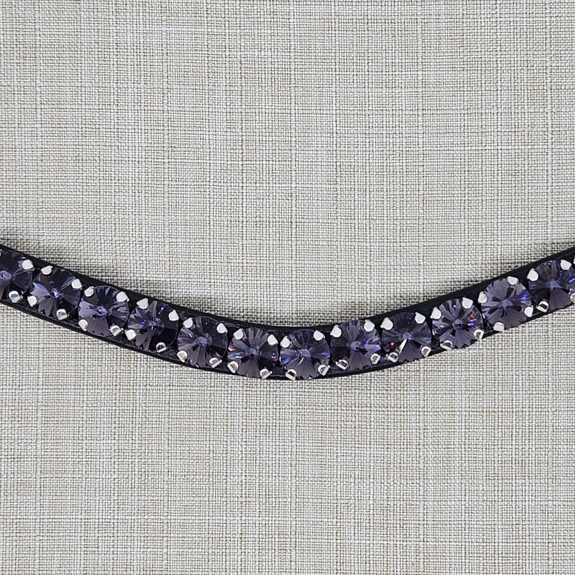 Close up view of a Black leather browband with purple crystals on a textured gray background. Browband is from KL Select Red Barn. Purple Passion.