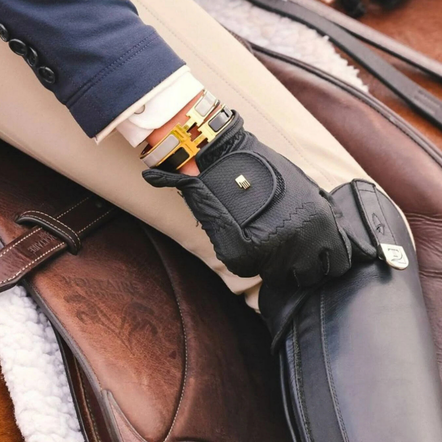 A close-up image of a black riding glove worn on a person&