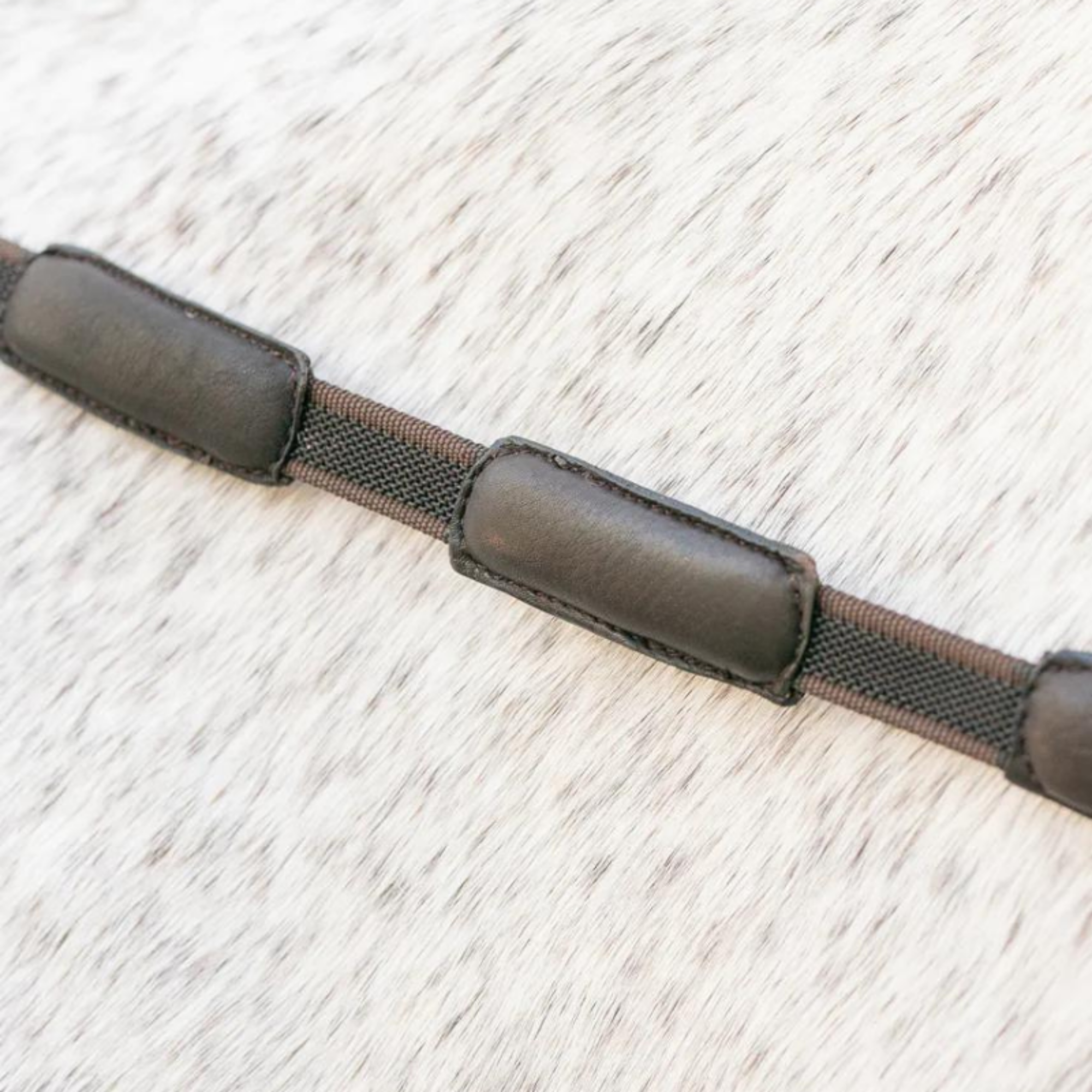 A close up view of brown correct connect reins. Padded grip and nylon inbetween.