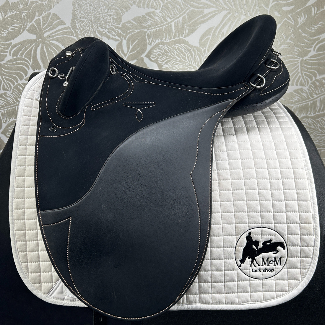Black Wintec Stock saddle with white quilted pad on a patterned background