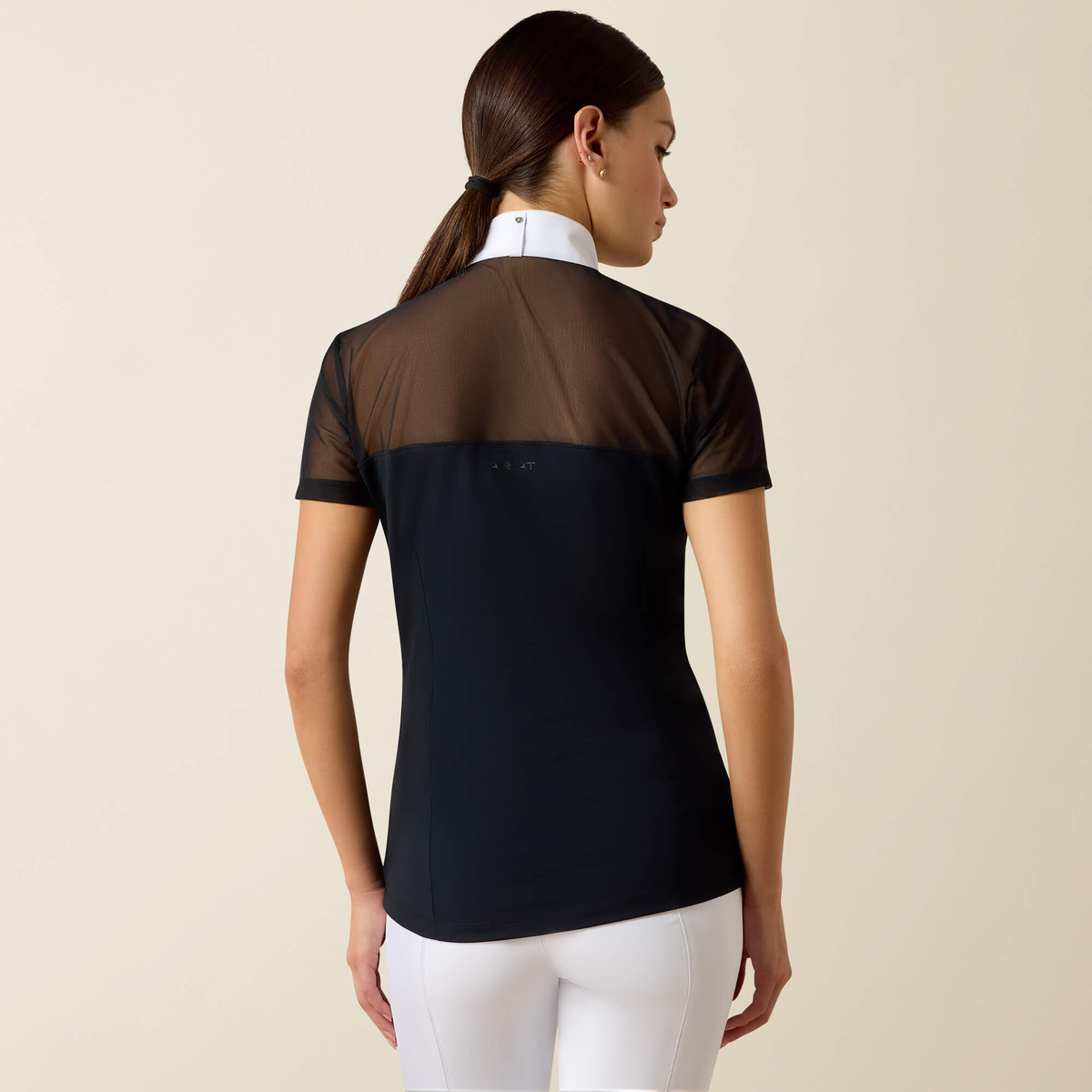 Back view of a young woman with dark, pulled back hair wearing an Ariat Allure Short Sleeve Show Shirt with a black bodice and white collar.