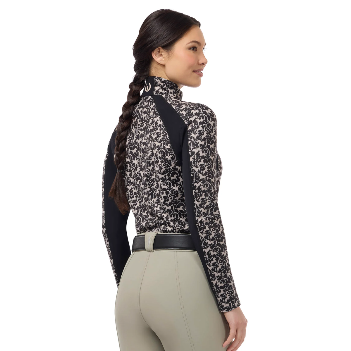 A woman shown from the back wearing a Kerrits Traverse quarter zip fleece tech top with a beige horse pattern, solid black ribbed sides & under sleeves paired with beige riding pants.