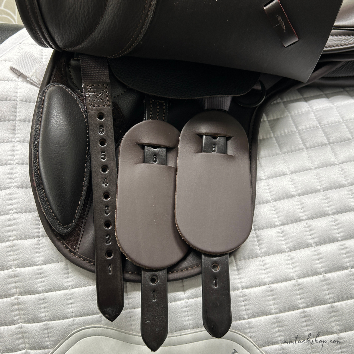 Closeup of the billets of this Thorowgood T9 Pony saddle on a white quilted saddle pad.