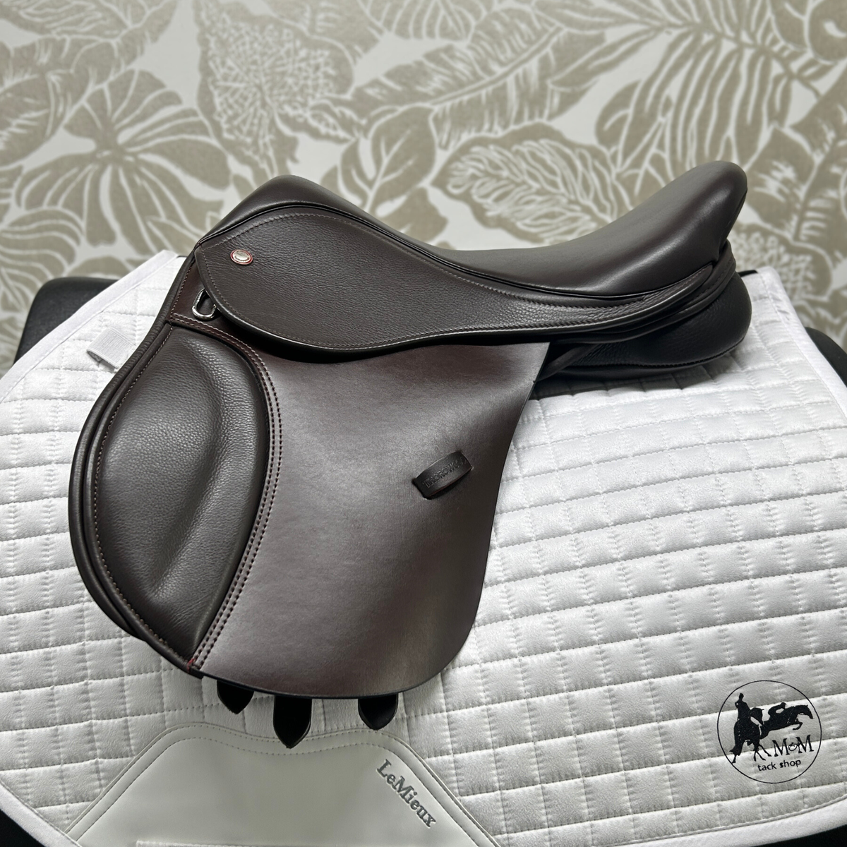 Thorowgood T9 Pony saddle on a white quilted saddle pad with a patterned gray background.