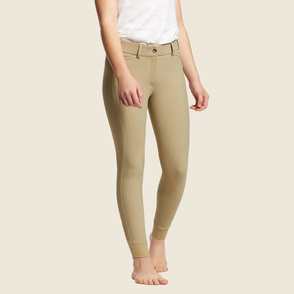 A child model wearing tan Ariat Kids Tri Factor EQ Grip Knee Patch Breeches, standing against a white background.