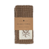A folded waffle-weave cotton towel in a warm taupe-brown color, wrapped with a brown kraft paper band labeled &