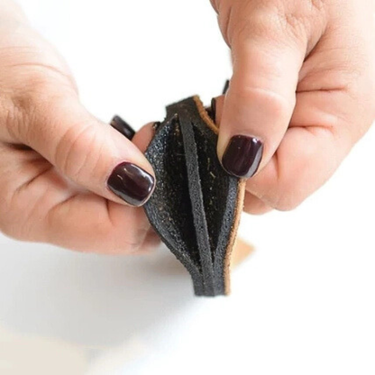 Close-up of hands holding a small black leather item on a white background