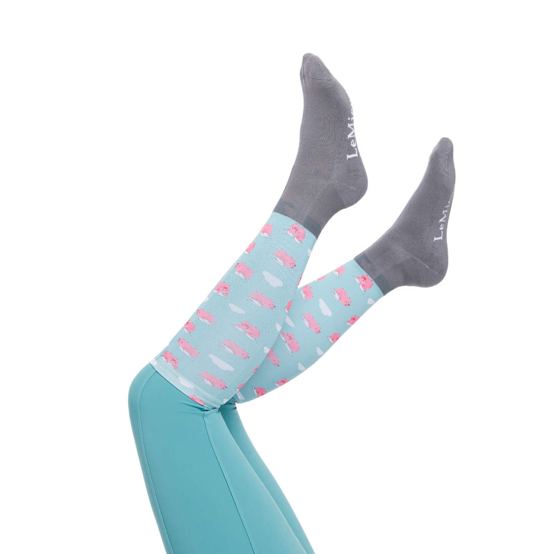 Image of LeMieux Footsie Junior  Boots Socks in their Flying Pig pattern on a models holding her legs up with a white background.