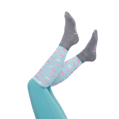 Image of LeMieux Footsie Junior  Boots Socks in their Flying Pig pattern on a models holding her legs up with a white background.