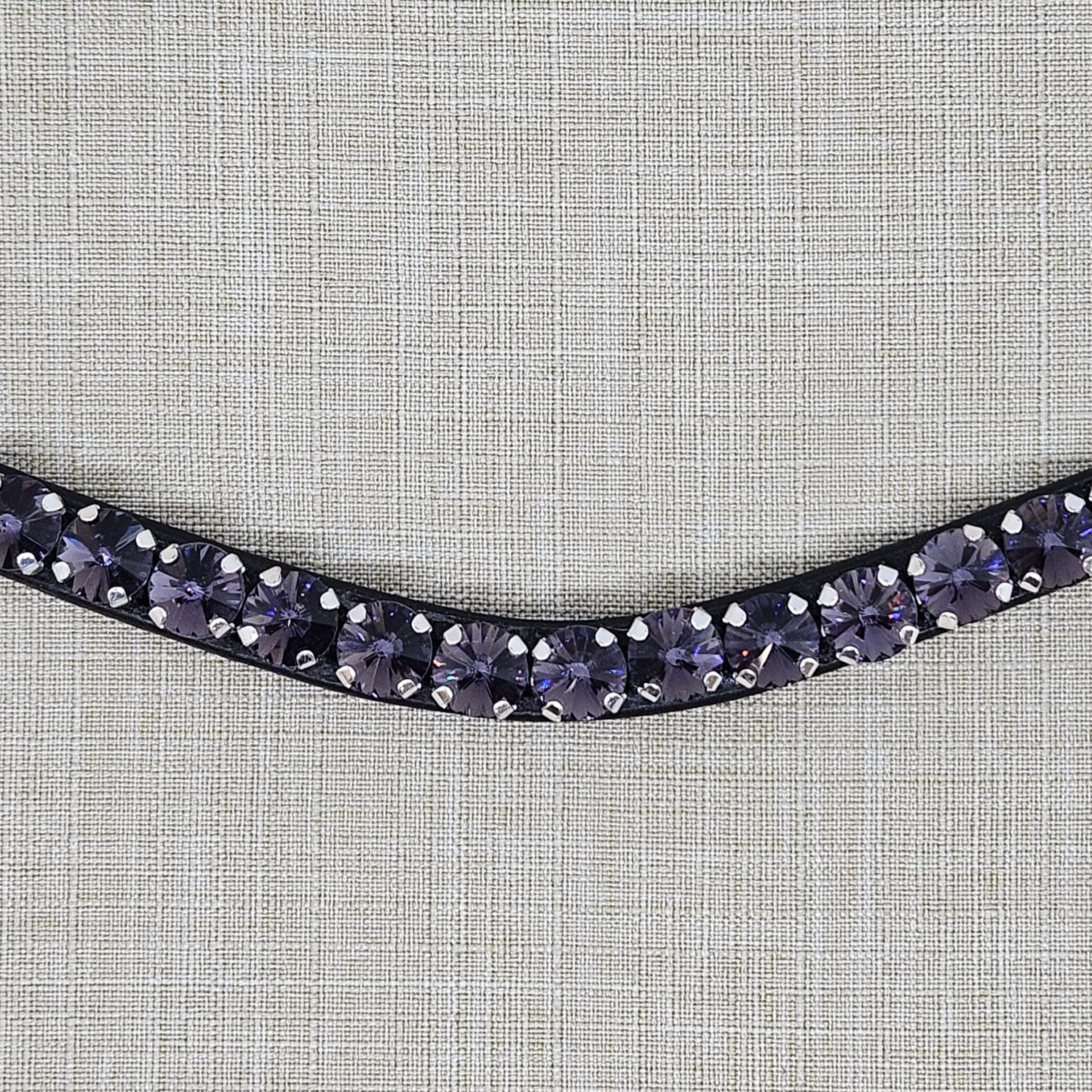 Close up view of a Black leather browband with purple crystals on a textured gray background. Browband is from KL Select Red Barn. Purple Passion.