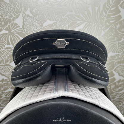Close-up of  the back of a black Wintec Stock Saddle saddle with a visible brand logo against a patterned background.