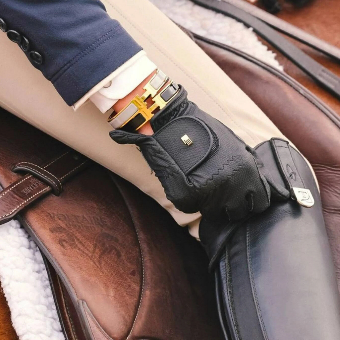 A close-up image of a black riding glove worn on a person&