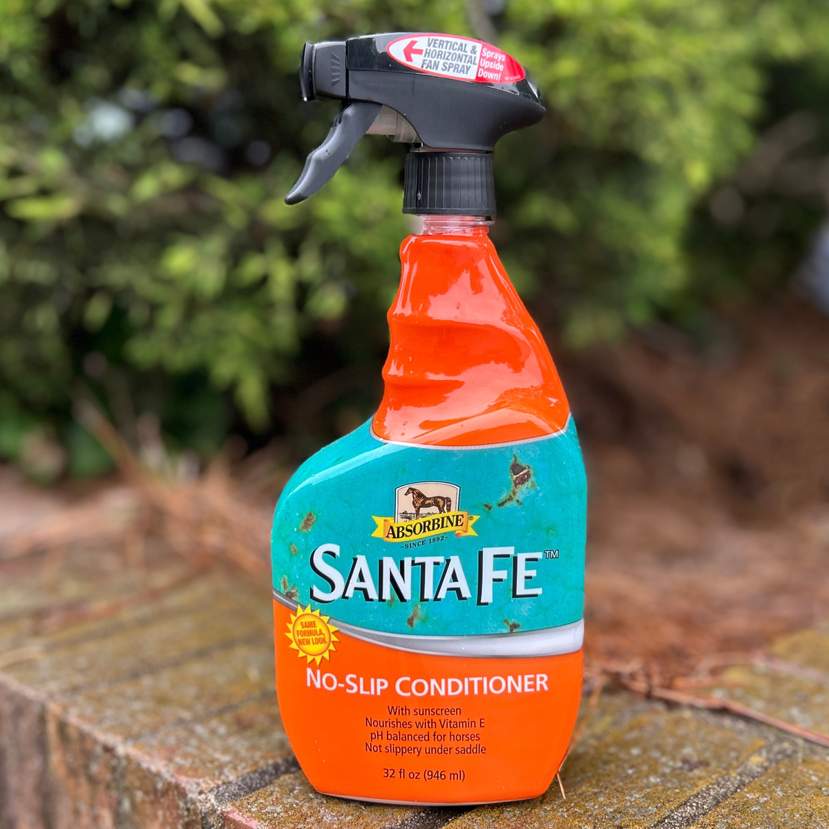 Absorbine Santa Fe no-slip conditioner spray bottle on a brick surface with greenery in the background.