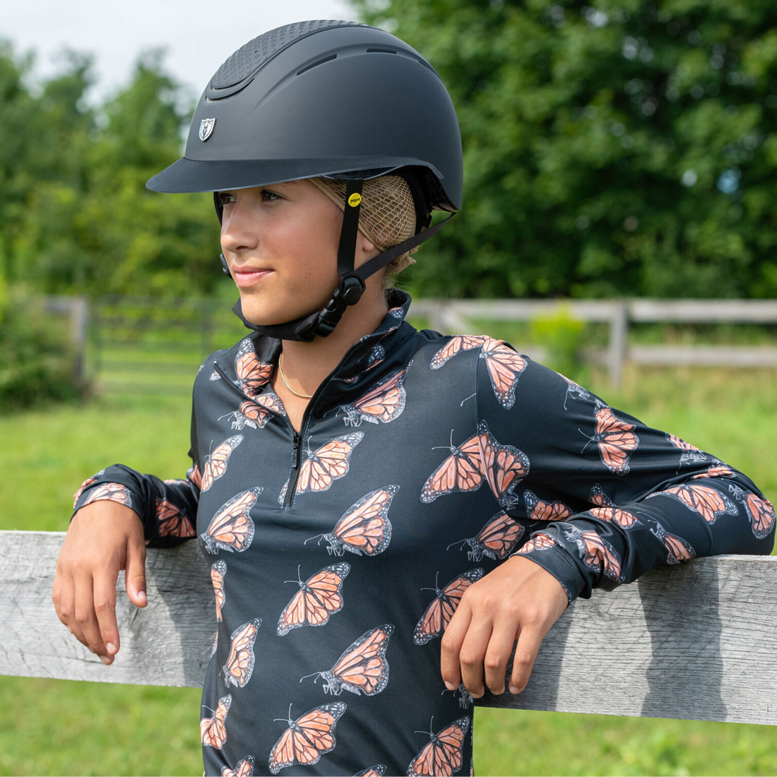 Lifestyle image of a female rider leaning against a fence wearing Tipperary&