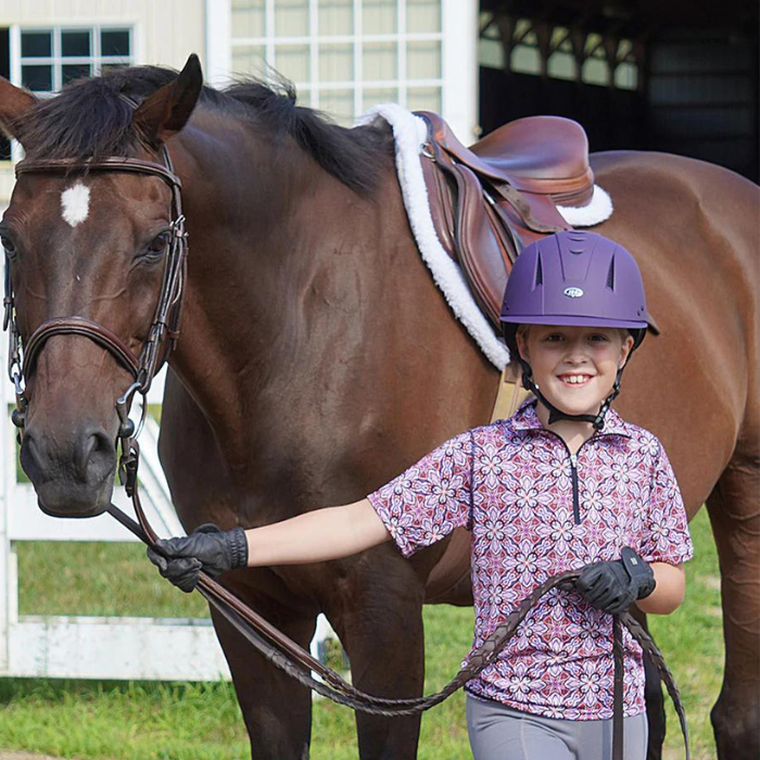 Girl holding a horse and wearing a purple IRH Equi-Pro Deluxe Schooling Helmet with Sun Visor (front view)