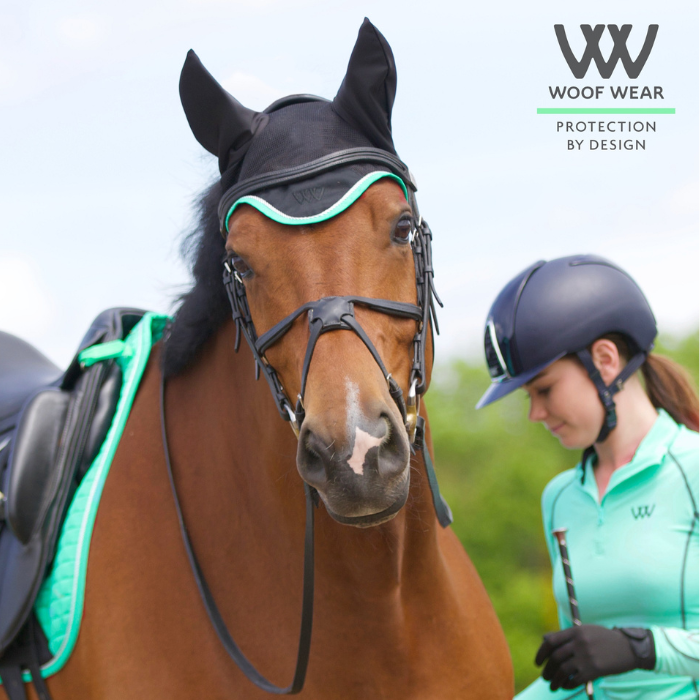 Girl holing a tacked up dressage horse wearing a Woof Wear Black &amp; Mint Ergonomic Fly Veil with silver rope edging and mint binding.