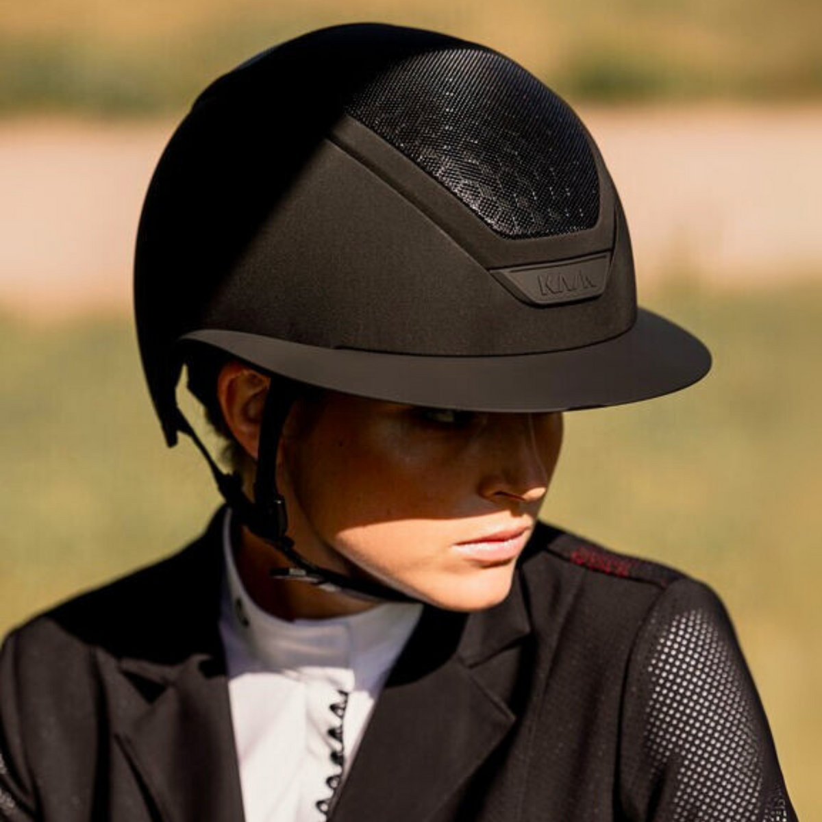 Female equestrian in show attire wearing a black KASK Star Lady Hunter riding helmet.