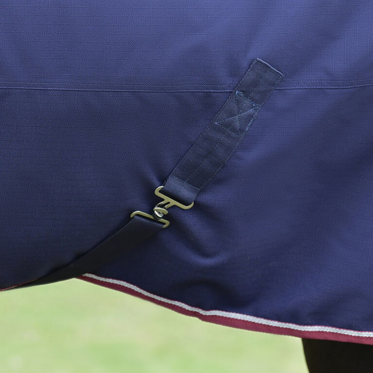 Close up of the belly bands on the Weatherbeeta Comfitec Essential Turnout Blanket in Navy with Burgundy trim.
