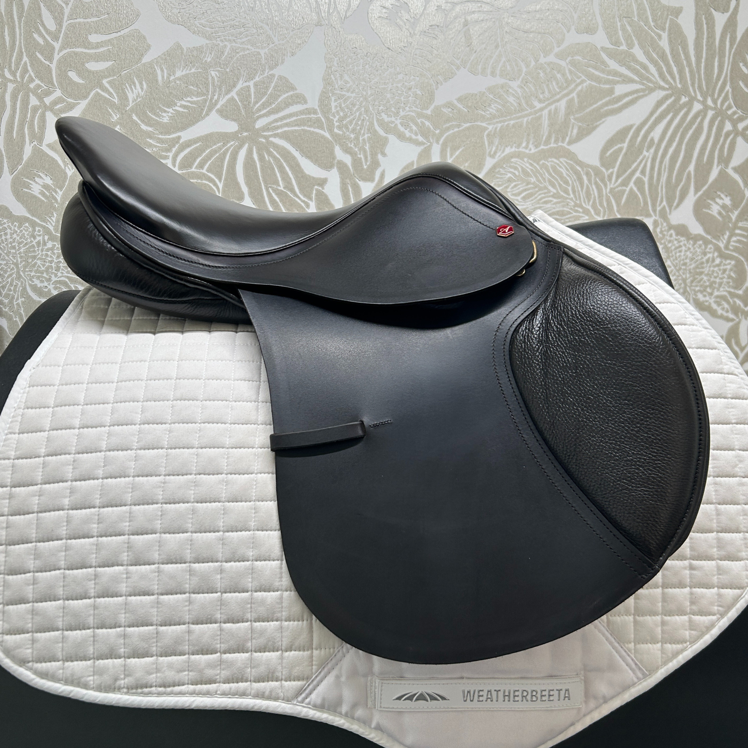 Demo dark Havana Albion flat, forward 17.5" jump saddle, medium wide, far side on a white quilted saddle pad. 