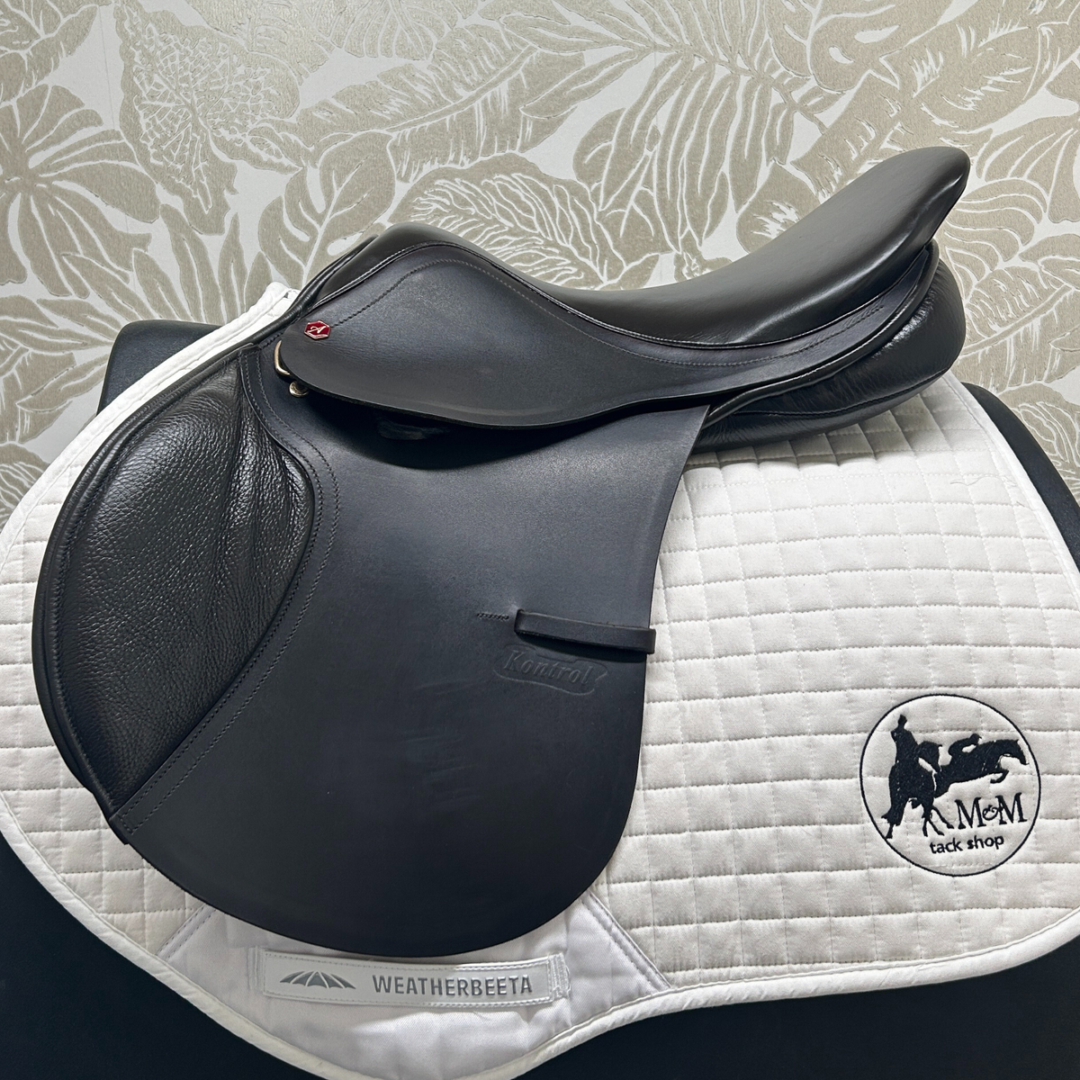 Demo dark Havana Albion flat, forward 17.5" jump saddle, medium wide, near side on a white quilted saddle pad. 