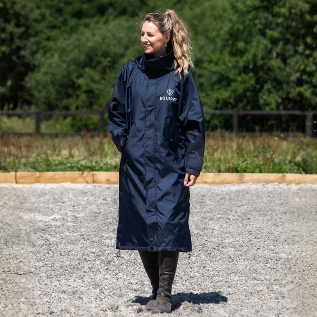 A woman wearing a navy blue EquiDry Evolution Mesh Lined  hooded raincoat with a white &