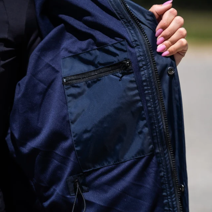 Close-up of a navy EquiDry Evolution Mesh Lined Coat being held open by a hand with pink manicured nails, showing a zippered pocket and outer zipper.