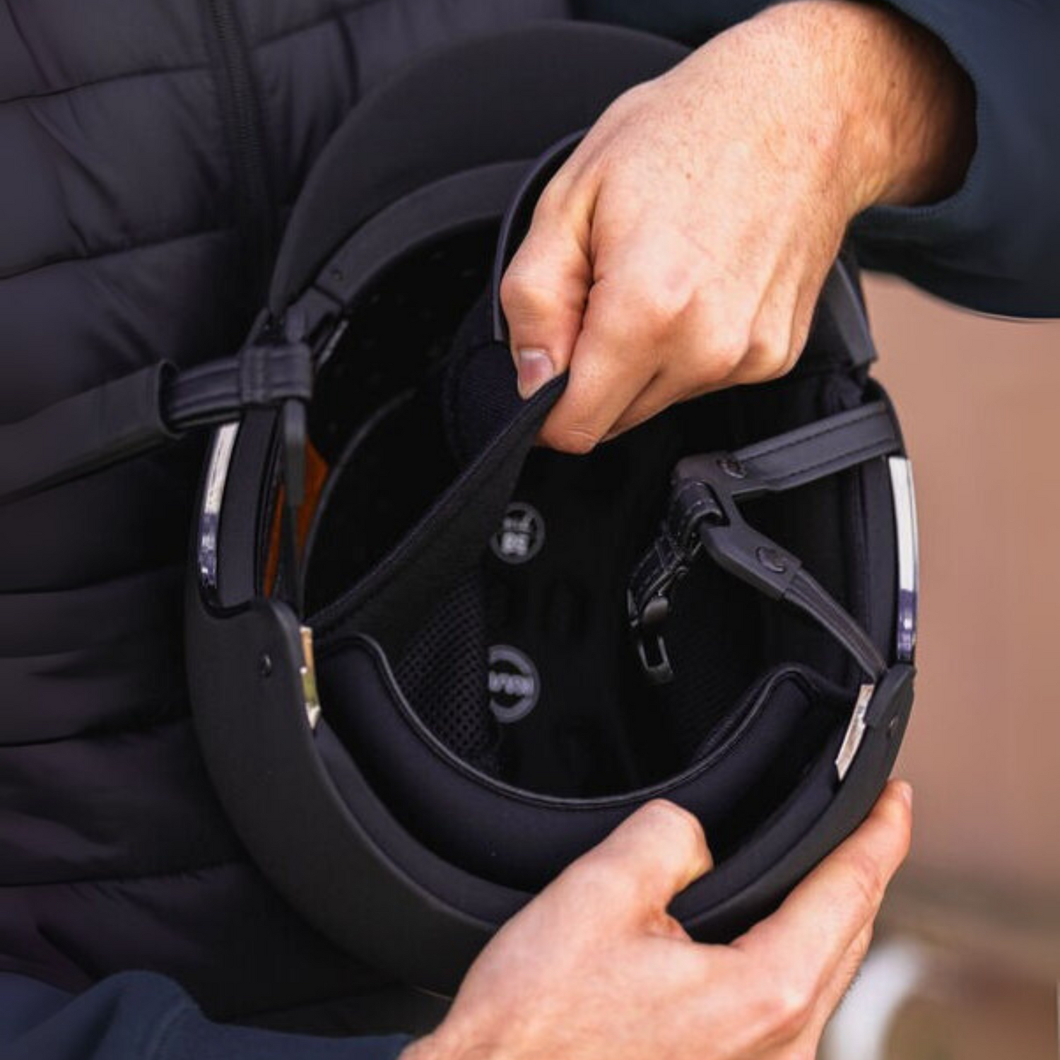 Person hold a black KASK help secruing KASKs dogma star helmet liner with padding. 