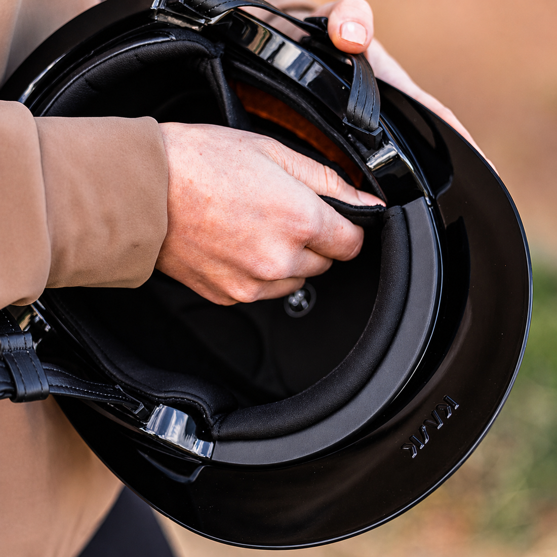 Close-up of a person holding a KASK Kooki helmet while inserting KASKs Kooki black helmet liner. 
