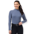 A woman modeling Kerrits Dusty Blue Align Textured Mock Neck Top, a slate blue long-sleeve mock top paired with black pants and a black belt, against a solid white background.