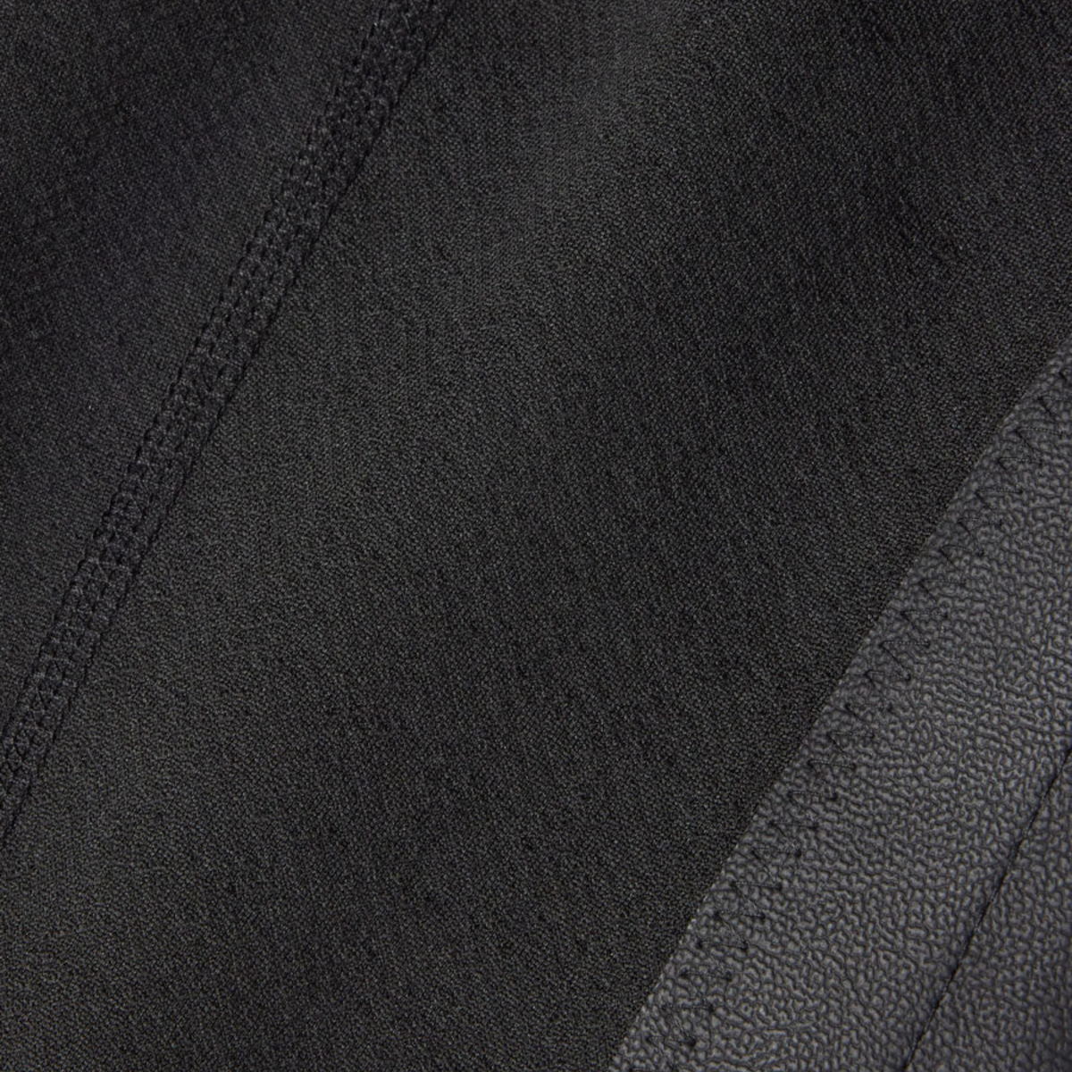 Close-up of Kerrits black Kids Fleece Lite II Knee Patch Riding Tights fabric with a diagonal seam and black pebbled leather-like grip.