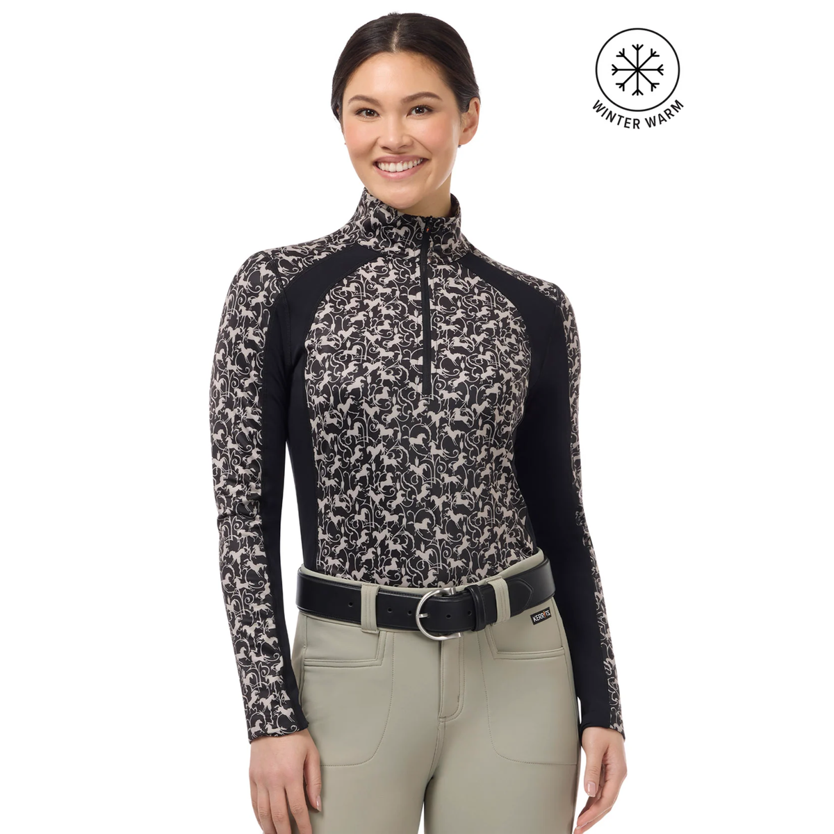 A woman modeling a long-sleeve Kerrits Traverse quarter zip fleece tech top with a beige horse pattern and solid black ribbed sides &amp; under sleeves paired with beige riding pants. A &