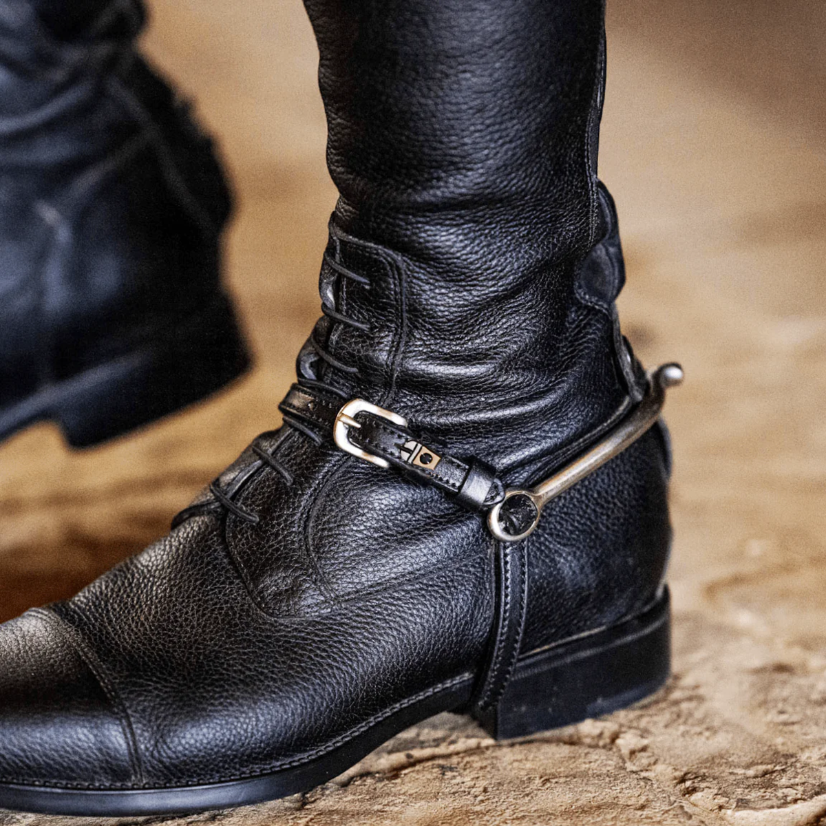 Mane Jane Frappe charm spur straps on an equestrian riding boot.