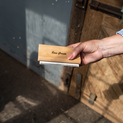 Hand holding a wooden Smart Grooming Ezee Groomer with &