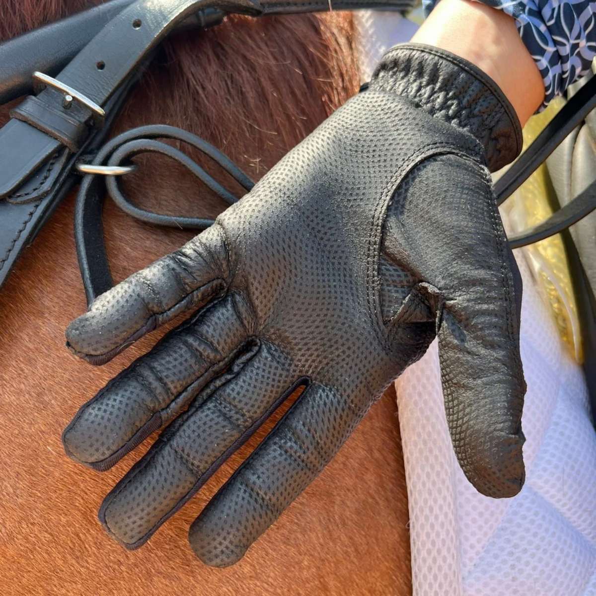 Black equestrian glove showing the grip on the palm and fingers.