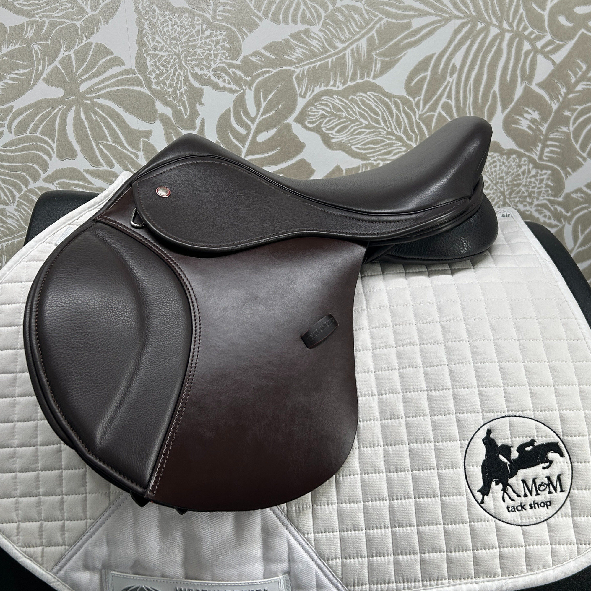 Thorowgood 15.5" T9 Pony Jump saddle on a quilted white saddle pad with a patterned gray background.