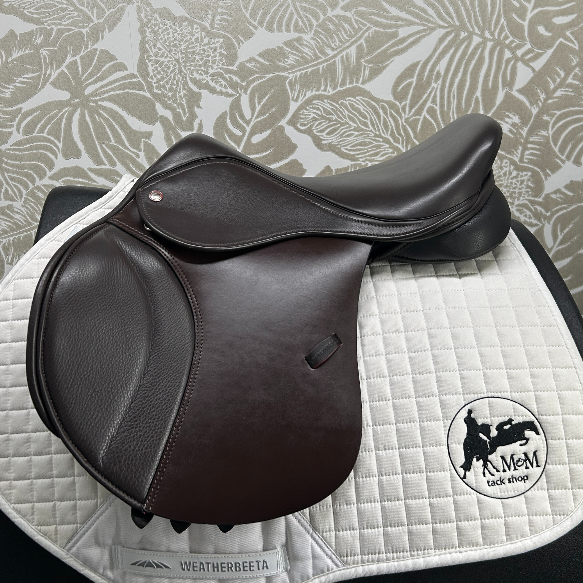 Thorowgood 16.5" T9 Pony Jump saddle on a quilted white saddle pad with a patterned gray background.