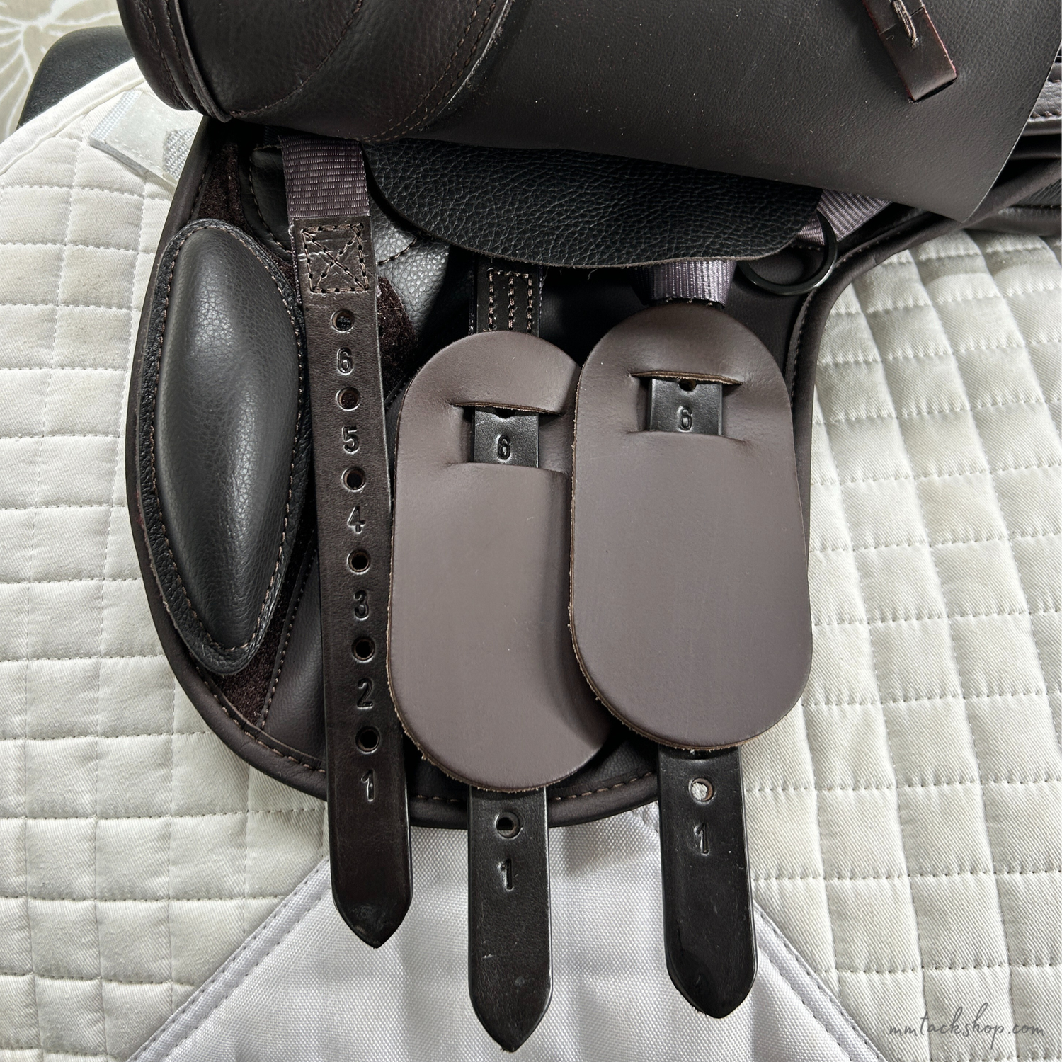 Closeup of the billets of this Thorowgood T9 Pony saddle on a white quilted saddle pad.