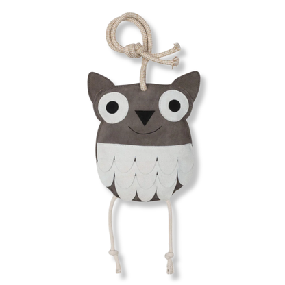 A plush owl stall toy with a dark grey head, large white eyes, a small black nose, and a white feather-like pattern on its body. It has a knotted beige rope handle on top and two hanging ties for legs at the bottom, shown against a plain white background.