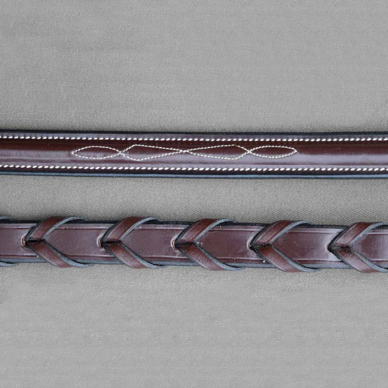 A close up detail of kl select black oak round raised fancy laced reins. 