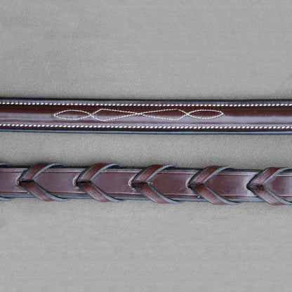 A close-up of brown kl select leather horse reins with white fancy stitching.